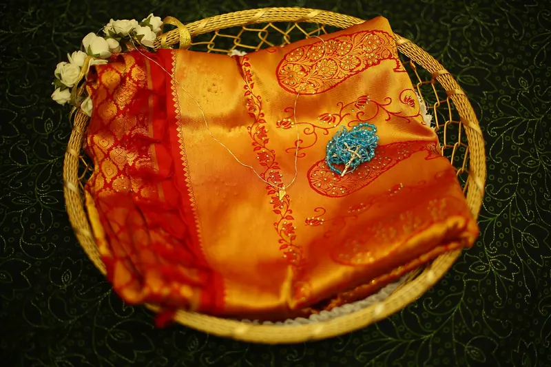 A manthrakodi saree in a basket with the rosary and the minnu on its seven threads